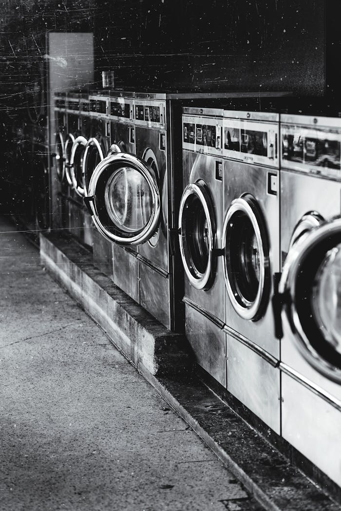 why-choose-us A row of industrial washing machines in an urban laundromat, showcasing steel finish.