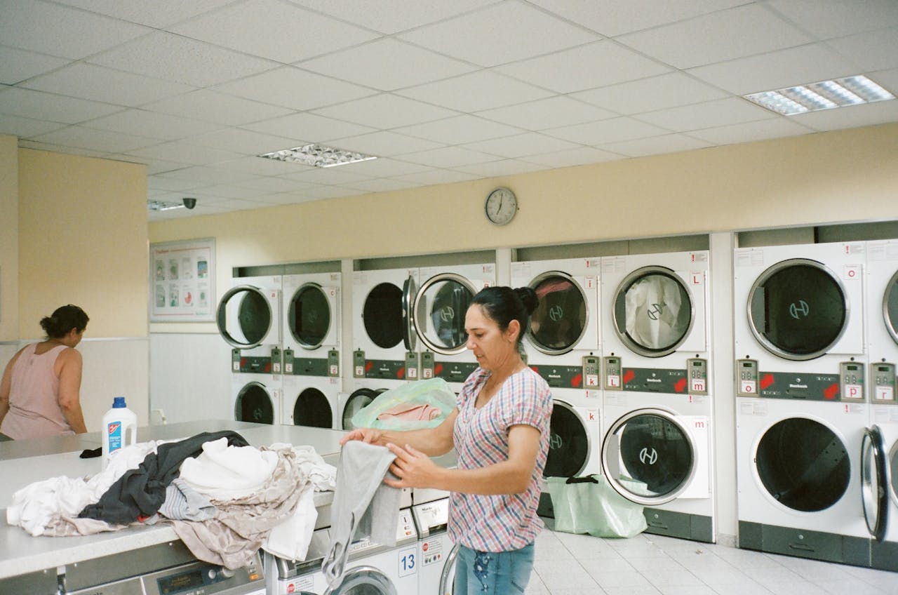 creative A woman folding clothes in a modern laundromat with various washing machines in the background.