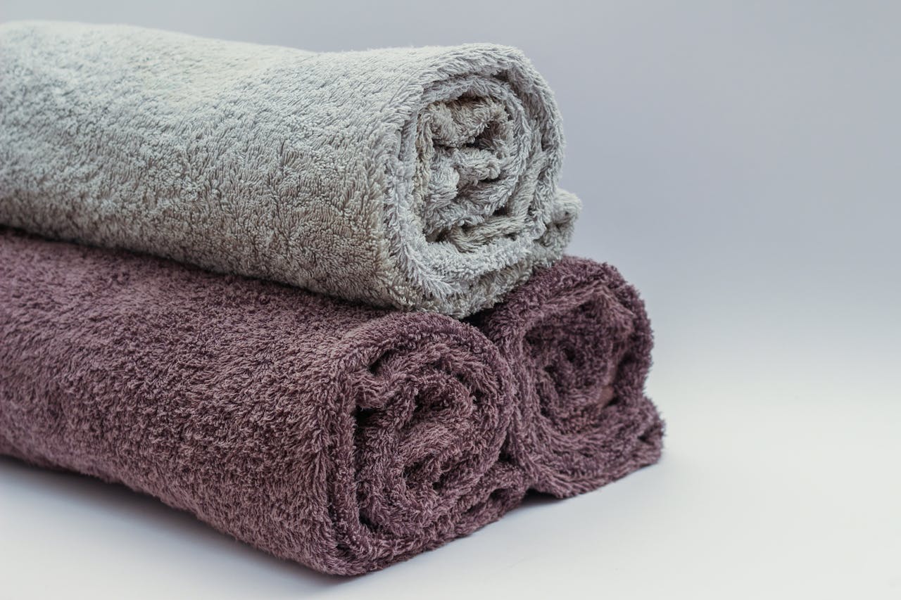 Services-03 Close-up of rolled bathroom towels in neutral tones, ideal for interior design or spa themes.